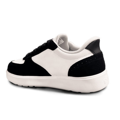 Black and white leather and suede sneaker, viewed from a back angle, showing the white sole and black heel.