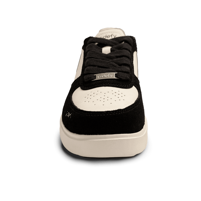 Black and white low-top sneaker with black laces and a silver 'g-defy' tag, featuring a perforated toe box.
