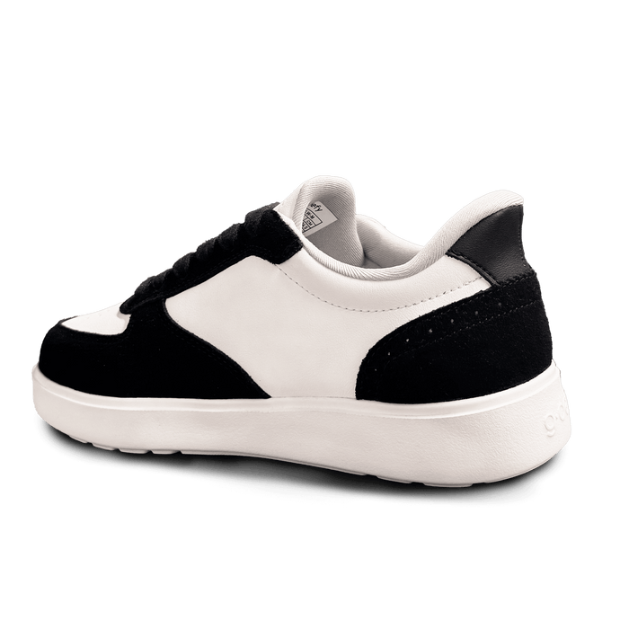 Black and white leather and suede sneaker, viewed from a back angle, showing the white sole and black heel.